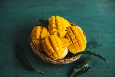 Yeşil bir ahşap üzerinde bir sepet içinde Mango