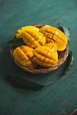 Yeşil bir ahşap üzerinde bir sepet içinde Mango