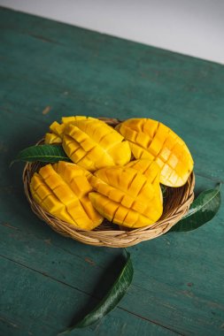 Yeşil bir ahşap üzerinde bir sepet içinde Mango