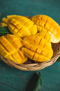 Yeşil bir ahşap üzerinde bir sepet içinde Mango