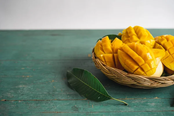 Yeşil bir ahşap üzerinde bir sepet içinde Mango