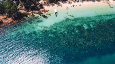 Adada berrak su, açık mavi deniz ve sahil.