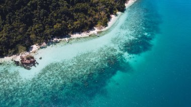 Adada berrak su, açık mavi deniz ve sahil.