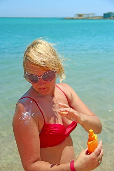 在异国情调的假期里 年轻女子涂上了保护性奶油 在日光浴期间使用奶油的金发女郎 皮肤健康的漂亮女人 涂上防晒霜 — 图库照片