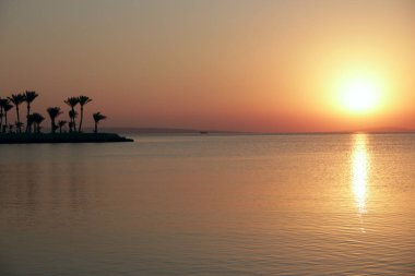 Denizin üstünde gün batımı. Okyanusun üzerinde güzel bir yaz çöküşü. Sabahın erken saatlerinde Kızıl Deniz ve turuncu gökyüzünün üzerindeki güzel, yakıcı günbatımı manzarası. İnanılmaz yaz günbatımı