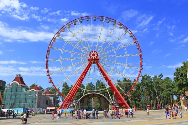Kharkiv / Ukrayna. 07 Ağustos 2016: dönme dolap ve insanlar yürümek Kharkiv Gorki Park. Şehir Parkı eğlenceleri ile yürüyüş insanlar. İnsanlar şehir parkında dinlen