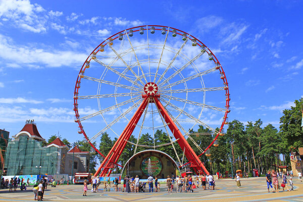 Kharkiv / Ukraine. 07 August 2016: Ferris wheel and people walk in Gorky park in Kharkiv. People walking in city park with entertainments. People have a rest in city park