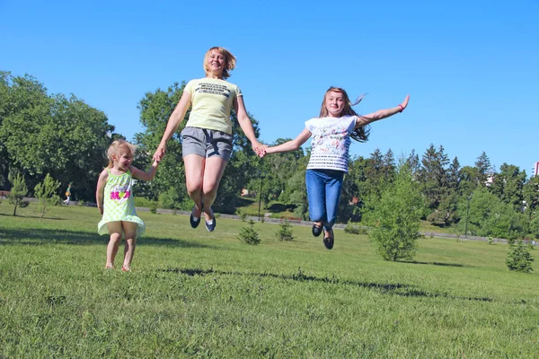 Feliz Madre Divirtiéndose Saltando Con Sus Hijas Sobre Hierba Verde —  Fotos de Stock