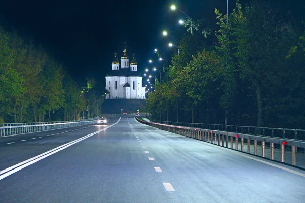 美しい教会の背景に夜の高速道路 夜間に道路標識を空にします 夜間照明の正教会 夜間道路にマーク 夜のアスファルト道路でチェルニヒウ市への入り口 — ストック写真