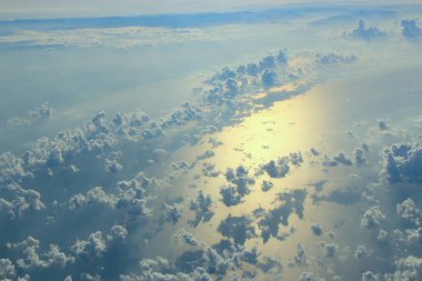 Pencere uçak uçan bulutlar ve deniz yüzeyi üzerinde güzel manzara. Bulutlar ile doğası. Beyaz bulutlar deniz su yüzeyi üzerinde hareket. Deniz yüzeyi yansıyan güneş manzara