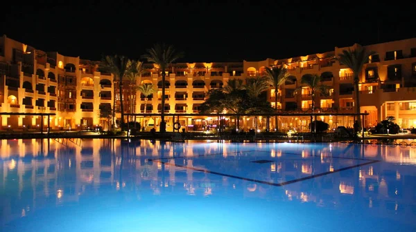 Hurghada/Mısır. 31 Temmuz 2018: havuz ve akşam otel tatil. İnsanlar akşam havuz yakınındaki sakin ol. Işıklar akşam otelin havuzu suda gecede yansıtılır. Hurghada resort Otel'in parlak ışıklar. İnsanlar relax havuz