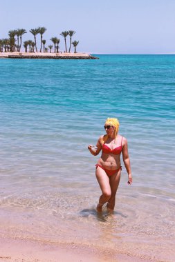 Kumsalda kahve içme dinlenme zevk çekici kız. Kahve fincanı deniz kum üzerinde olan kadın. Güzel kadın deniz kenarında rahatlatıcı. Kız zevk kumsalda içme kahve getirin. Deniz ayakta rahatlatıcı kadın