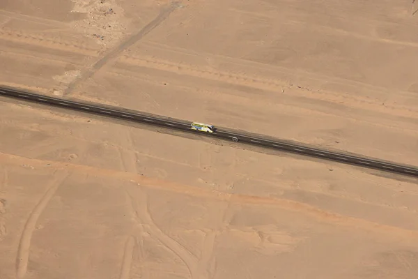 View from window of plane on way in desert. Aerial view of bus traveling along highway in desert. Aerial view of highway road in desert. Road trip travel adventure. Highway crossing through sandy land