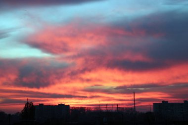 Koyu kırmızı günbatımı çok öykülü ev yukarıda. Akşam cityscape. Şehir manzarası. Kasabada alacakaranlıkta. Alacakaranlık vermilyon gün batımı ile. Akşam şehir üzerinde büyük pembe bulut