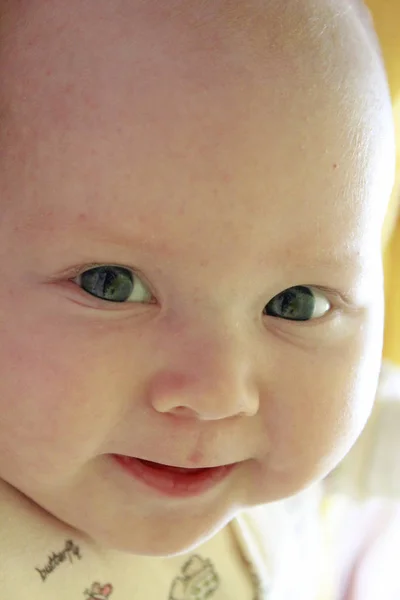 Портрет улыбающегося ребенка с голубыми глазами. Новорожденный ребенок смотрит на мать — стоковое фото