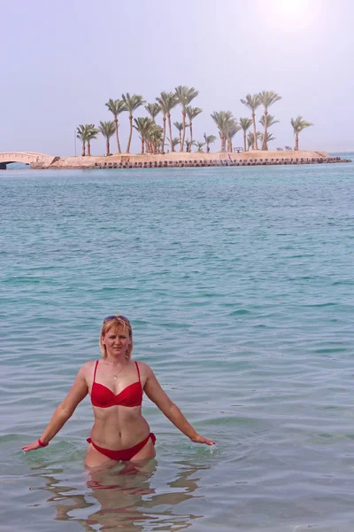 Flicka njuter resten i havet. Kvinnan avslappnande i havet nära ön med palms träd — Stockfoto