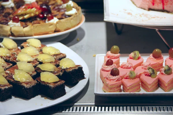파인애플, 키 위, 포도로 장식한 케이크를 먹는다. 다양 한 디저트 선택 — 스톡 사진