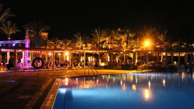 Yüzme Havuzu ve gece otel tatil günlerinde. İnsanlar akşam havuz yakınındaki sakin ol