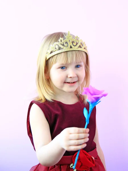 Aranyos lány a korona a fején rózsaszín rózsa kínál. A gyönyörű ruhát mosolygó gyermek — Stock Fotó
