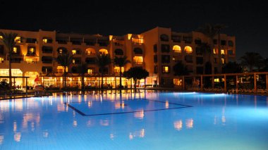 Yüzme Havuzu ve gece otel tatil günlerinde. İnsanlar akşam havuz yakınındaki sakin ol