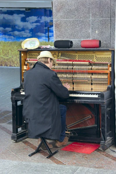 Hudebník hraje piano venku. Pianista, vydělávat na živobytí tím, že hraje s klavírem — Stock fotografie