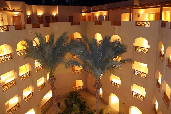 Palm trees growing near resort building in evening — Stock Photo, Image