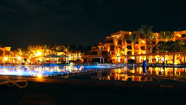 Piscina y hotel nocturno. La gente se relaja por la noche cerca de la piscina — Foto de Stock