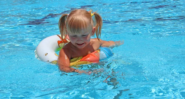 Niña sonriente con trenzas nadando en la piscina acostada en círculo inflable Imagen de archivo