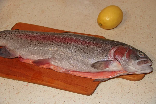 Pesce trota iridea pronto per la cottura con limone. Piatto di pesce saporito — Foto Stock