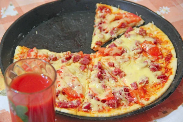 Tasty cut pieces of pizza on plate and glass of tomato juice. Cooked fast food — Stock Photo, Image