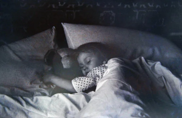 Vintage photo of little sleeping girl embracing toy