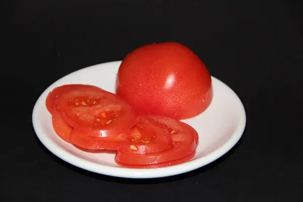 Plasterki pomidora na białej płycie izolowane na czarnym tle — Zdjęcie stockowe