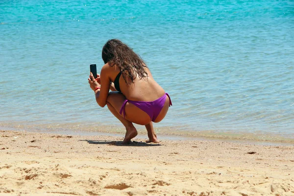 Kadın turist güneşleniyor ve tatilde sahilde fotoğraf çekiyor. — Stok fotoğraf