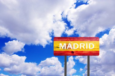 Bulutlu gökyüzü manzaralı Madrid 'e giden yolu gösteren tahta levhayı imzalayın. Tahta masadaki yol tabelası yerleşim yerini gösteriyor. Masada İspanyol bayrağı resmi olan Madrid 'i imzala