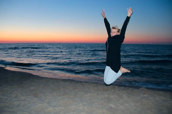 Happy woman jumped on the seashore at sunset. Girl jumping on the seashore at sunset. Joyful woman jumping on sunset background. Happy traveller on sand of Baltik sea