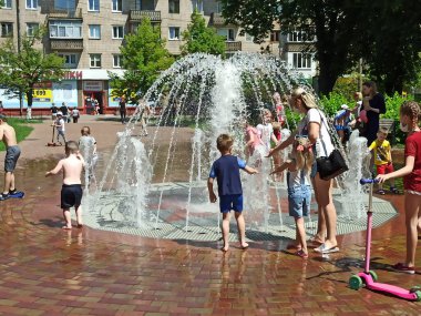 Chernihiv / Ukrayna. 02 Temmuz 2020: Chernihiv / Ukrayna. 02 Temmuz 2020: Çocuklar sıcak yaz gününde şehir çeşmeleriyle eğleniyorlar. Çocuklar sıcak yaz gününde su jetleriyle oynarlar. Şehir sıcağı. Sıcak yaz günü
