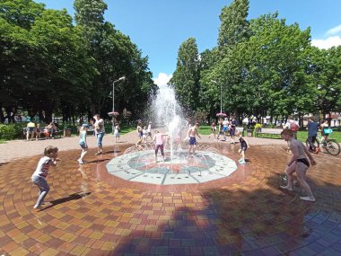 Chernihiv / Ukrayna. 02 Temmuz 2020: Çocuklar sıcak yaz gününde şehir çeşmeleriyle eğleniyorlar. Çocuklar sıcak yaz gününde su jetleriyle oynarlar. Şehir sıcağı. Sıcak yaz günü