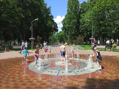 Chernihiv / Ukrayna. 02 Temmuz 2020: Çocuklar sıcak yaz gününde şehir çeşmeleriyle eğleniyorlar. Çocuklar sıcak yaz gününde su jetleriyle oynarlar. Şehir sıcağı. Sıcak yaz günü