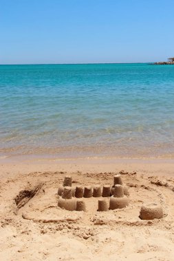 Deniz kıyısındaki kumsal piramidi. Kum piramidi deniz kenarında inşa edildi. Çocukça işler. Deniz kıyısında çocuklar tarafından yapılmış kumdan evler. Yaz tatili. Rahatlatıcı bir kavram. Baltık Denizi 'nde Dinlenme