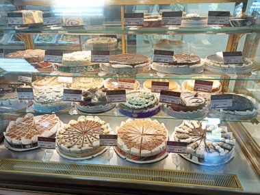 Chernihiv - Ukrayna. 28 Şubat 2020: Vitrinde dondurma olan çikolatalı pasta ve bardak. Bir pastanede satılan pastaların çeşitleri. Pasta dükkanında pastalar sergileniyor.