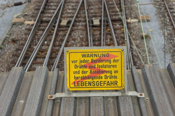 attention high voltage sign near train tracks in german language