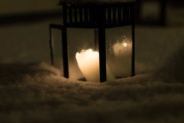 Vela queimando em lanterna de pé na neve à noite — Fotografia de Stock