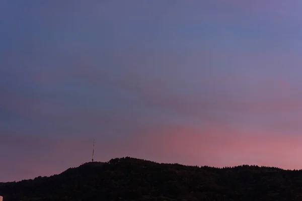 Ηλιοβασίλεμα με βιολετί ουρανό και βουνό με πύργο τηλεόρασης — Φωτογραφία Αρχείου