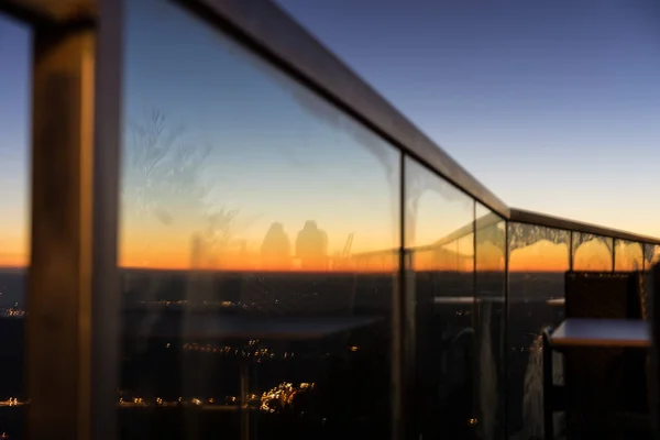 Ηλιοβασίλεμα με γυάλινη κουπαστή θέα της πόλης και καθρεφτίζονται Σιλουέτ — Φωτογραφία Αρχείου