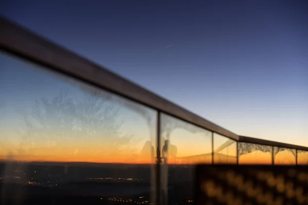 Ηλιοβασίλεμα με γυάλινη κουπαστή θέα της πόλης και καθρεφτίζονται Σιλουέτ — Φωτογραφία Αρχείου