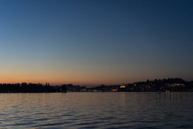 Şehir arka plan ile tekneyle görüntülenen Lucerne Gölü üzerinde günbatımı