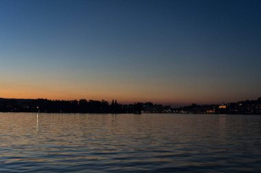 Şehir arka plan ile tekneyle görüntülenen Lucerne Gölü üzerinde günbatımı