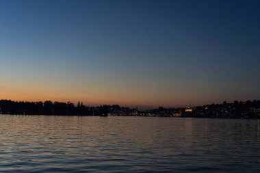 Şehir arka plan ile tekneyle görüntülenen Lucerne Gölü üzerinde günbatımı