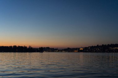 Şehir arka plan ile tekneyle görüntülenen Lucerne Gölü üzerinde günbatımı