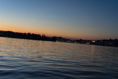 Şehir arka plan ile tekneyle görüntülenen Lucerne Gölü üzerinde günbatımı